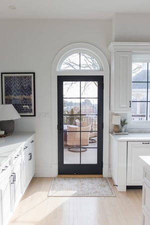 The arched manor kitchen has a black door with equal grilles.