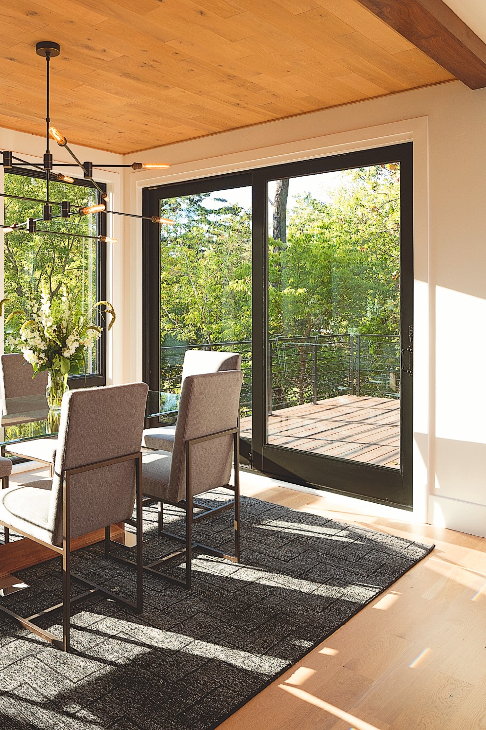 A dramatic black patio door looking out to a deck and lush yard. This is an A-series sliding glass replacement door.