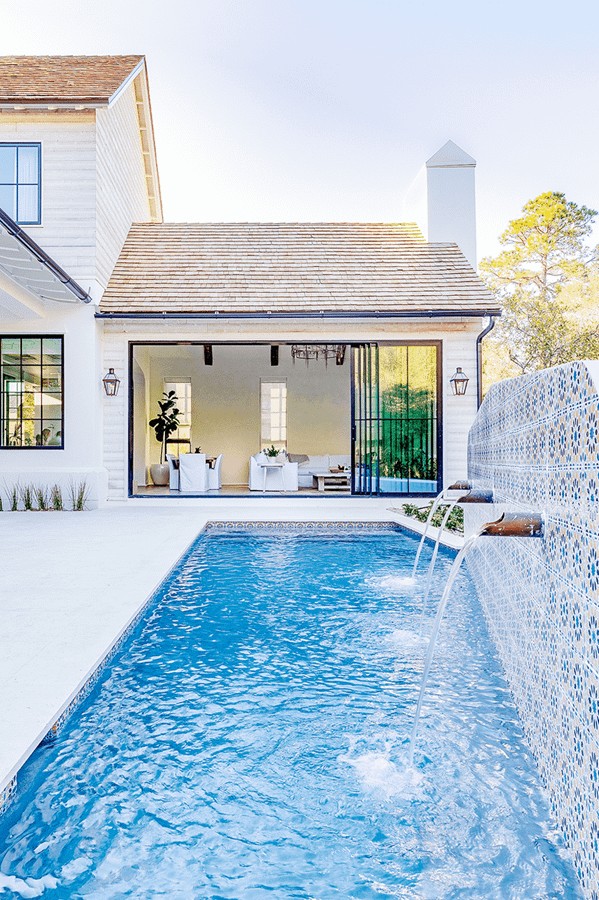 A pool with some multipanel doors behind it, It is a lovely blue pool.