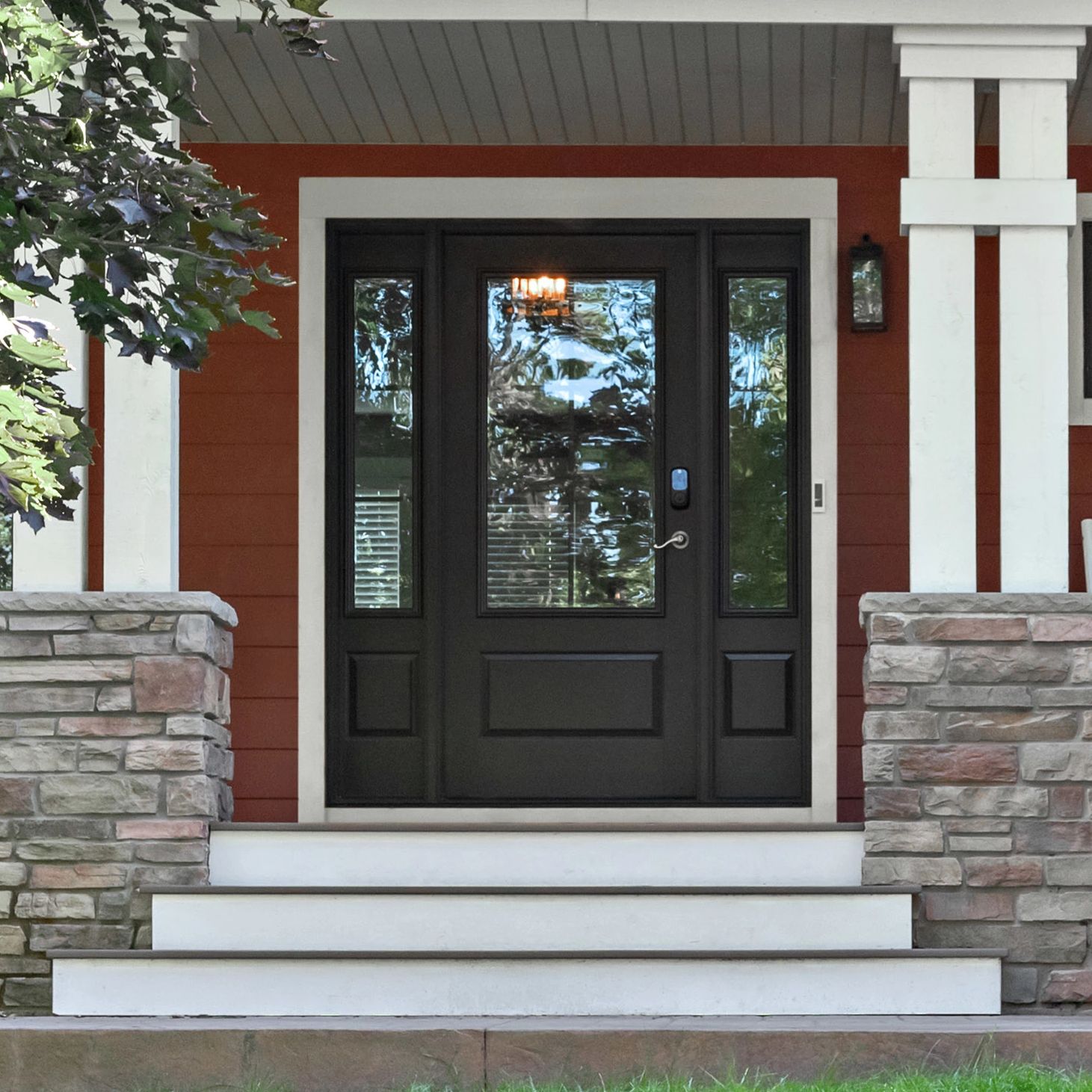 An Ensemble entry door with dual sidelights in black. The house is red and the steps are white.