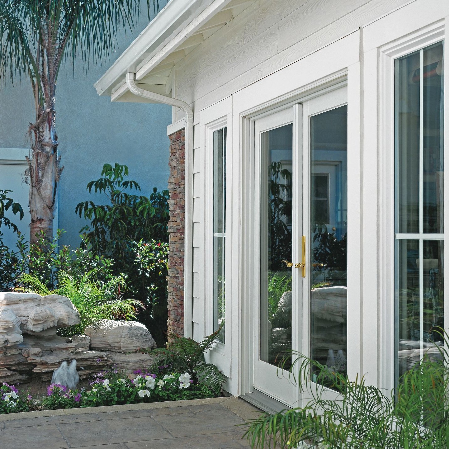 White French doors without grilles. The doors are hinged, and the hardware is bright brass.
