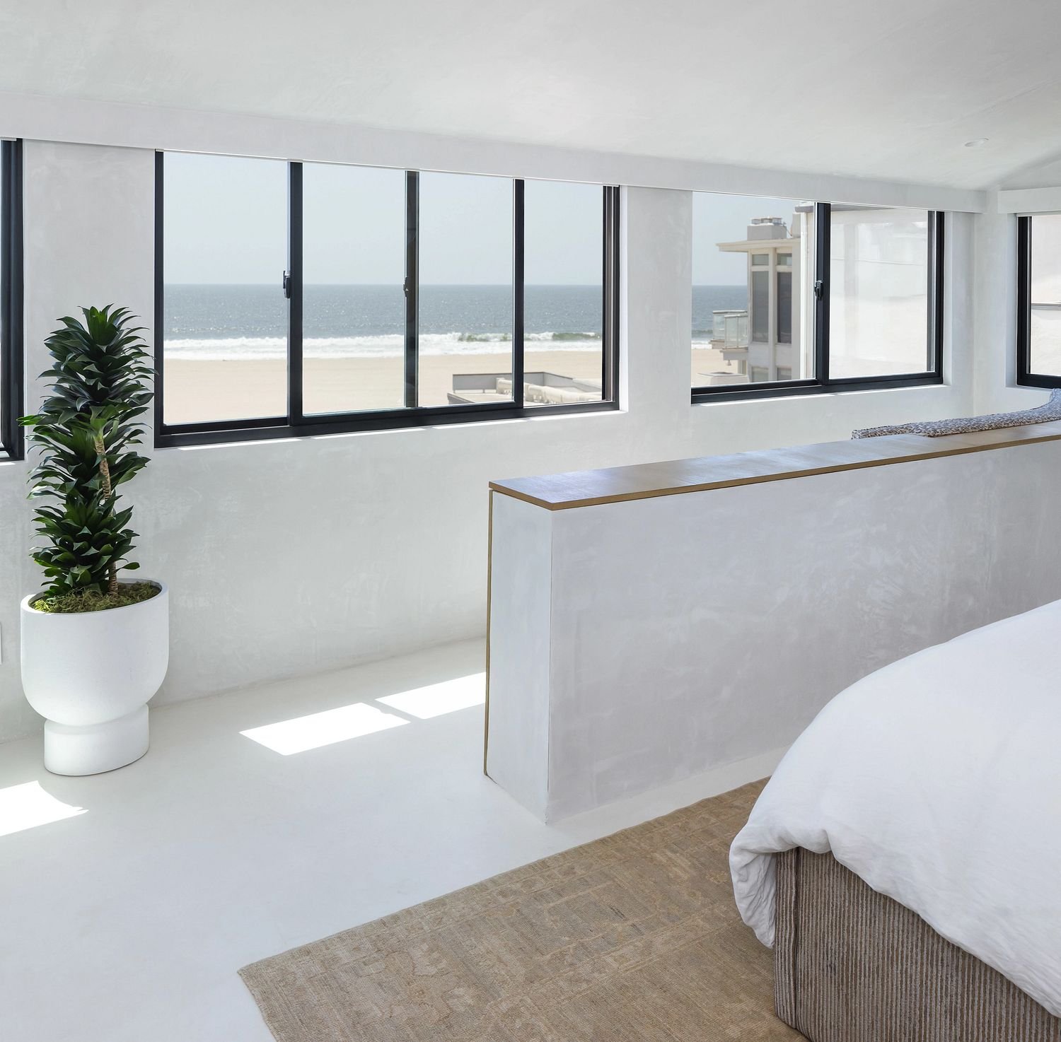 A series of sliding windows in a bedroom looking out to a beach.