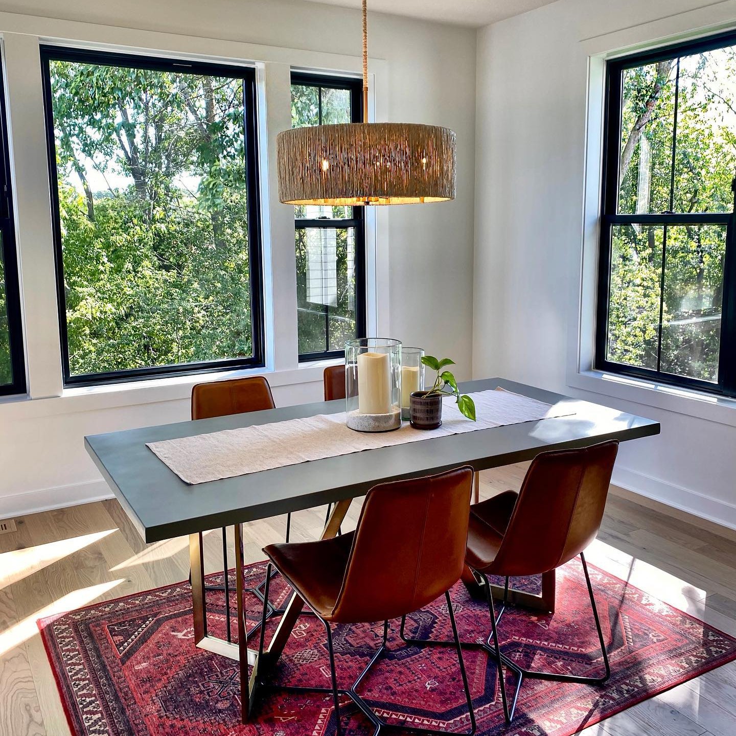 Picture window flanked by double hung windows with black frames in a dining room