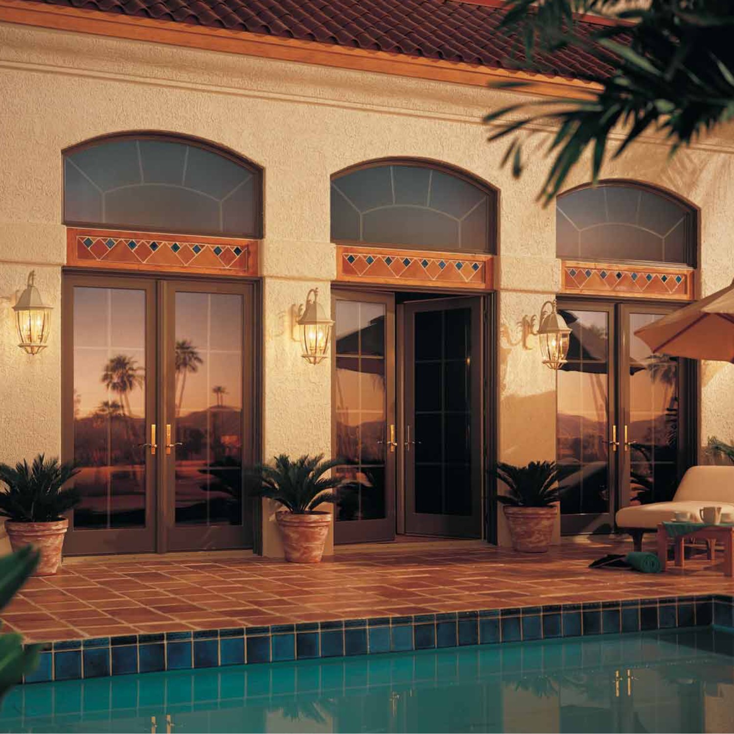 Equal leg arch windows in terratone above sets of patio doors looking out onto a blue swimming pool.