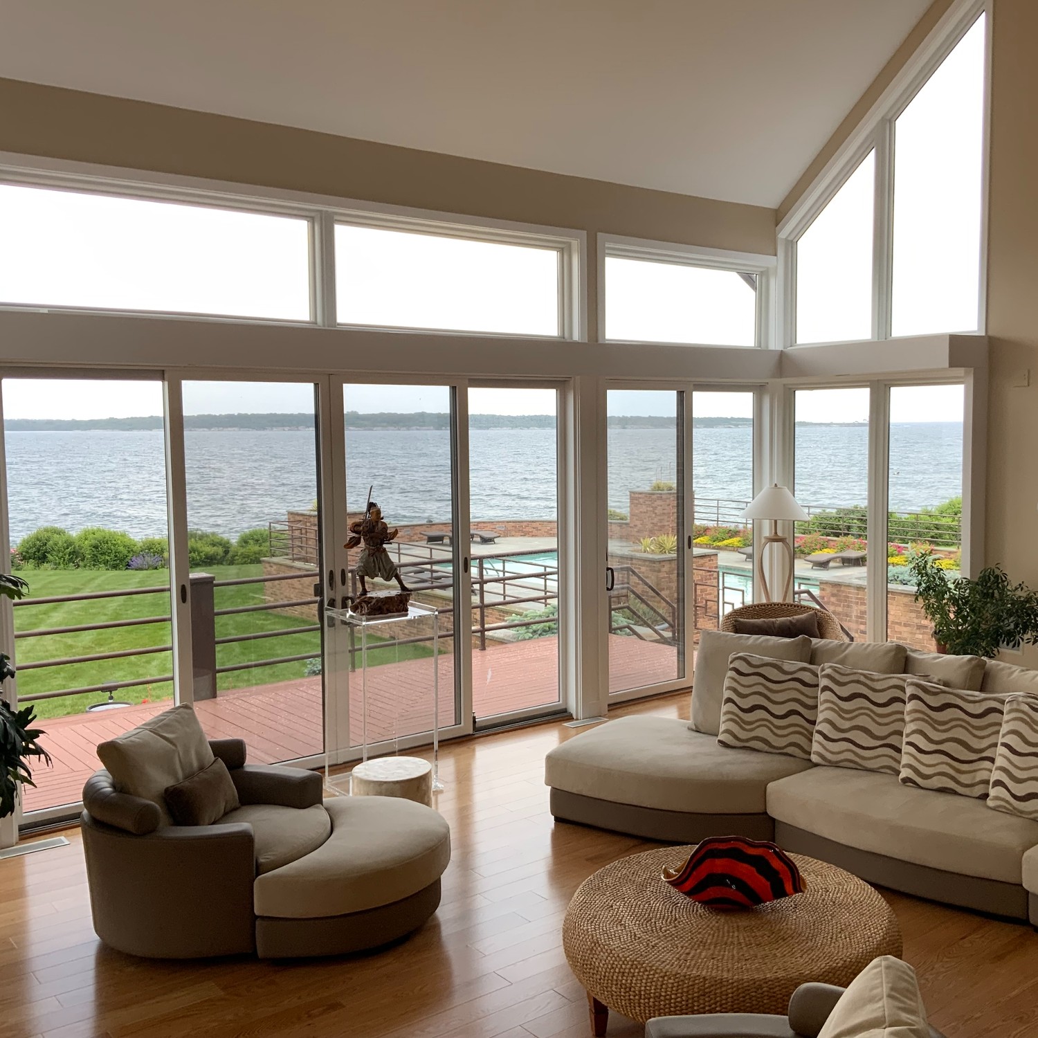Specialty windows in an all glass living room overlooking a lush lawn