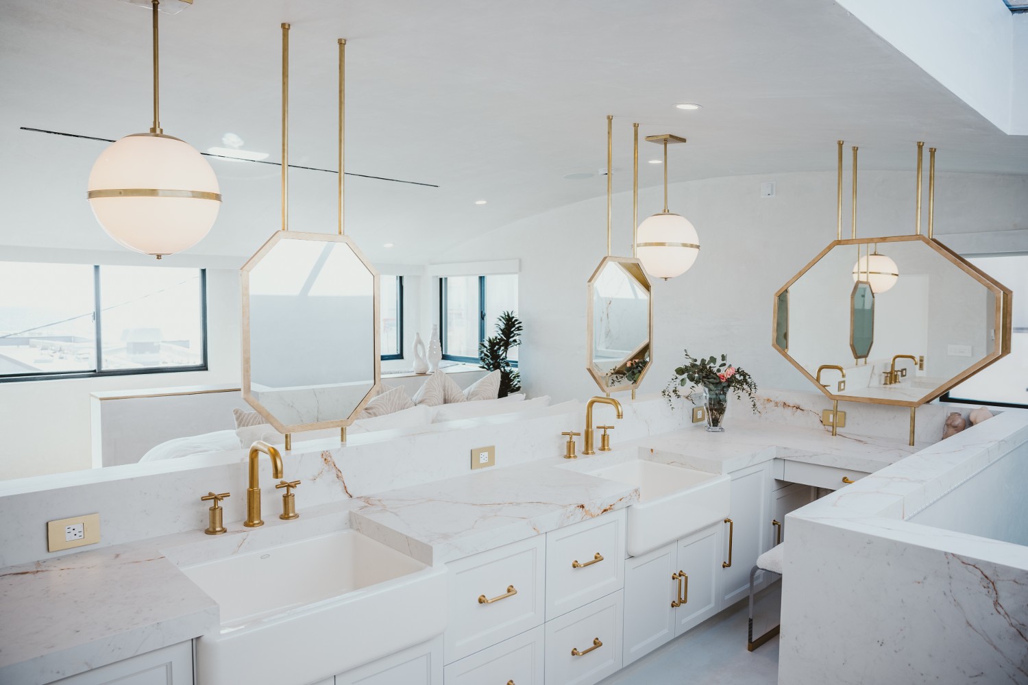 The bathroom area in the primary suite in Breegan Jane's california beach house. It is all white with gold fixtures.
