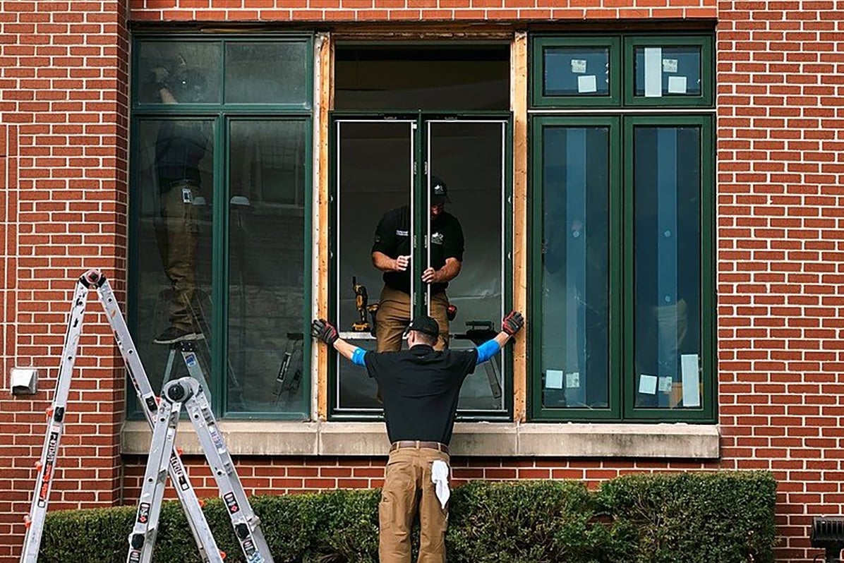 Installers replacing windows on the Kansas City Hope Lodge. One is outside working, one is inside working.